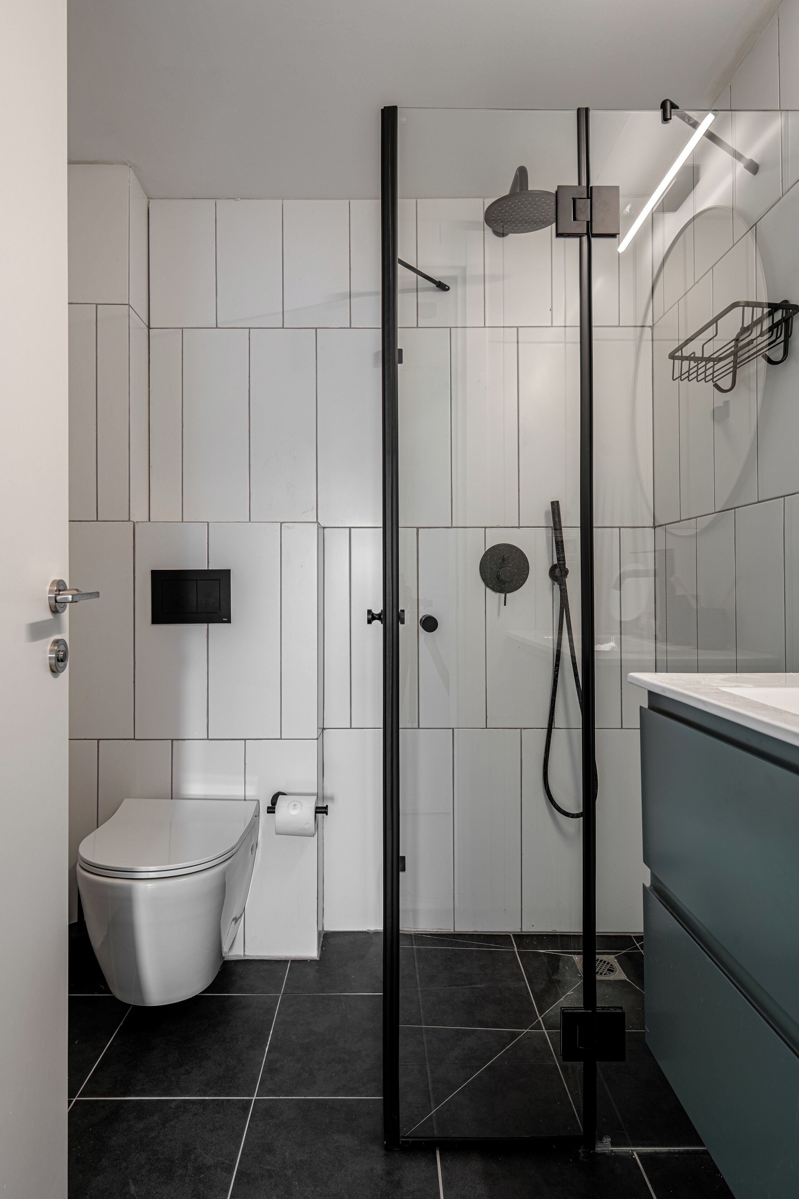 A modern bathroom with a glass-enclosed shower, a toilet, and a sink.
