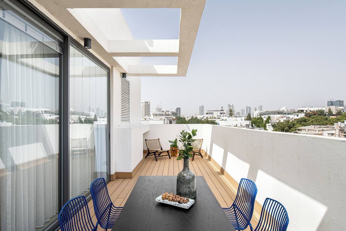 A balcony with a table, chairs, and a vase with flowers.