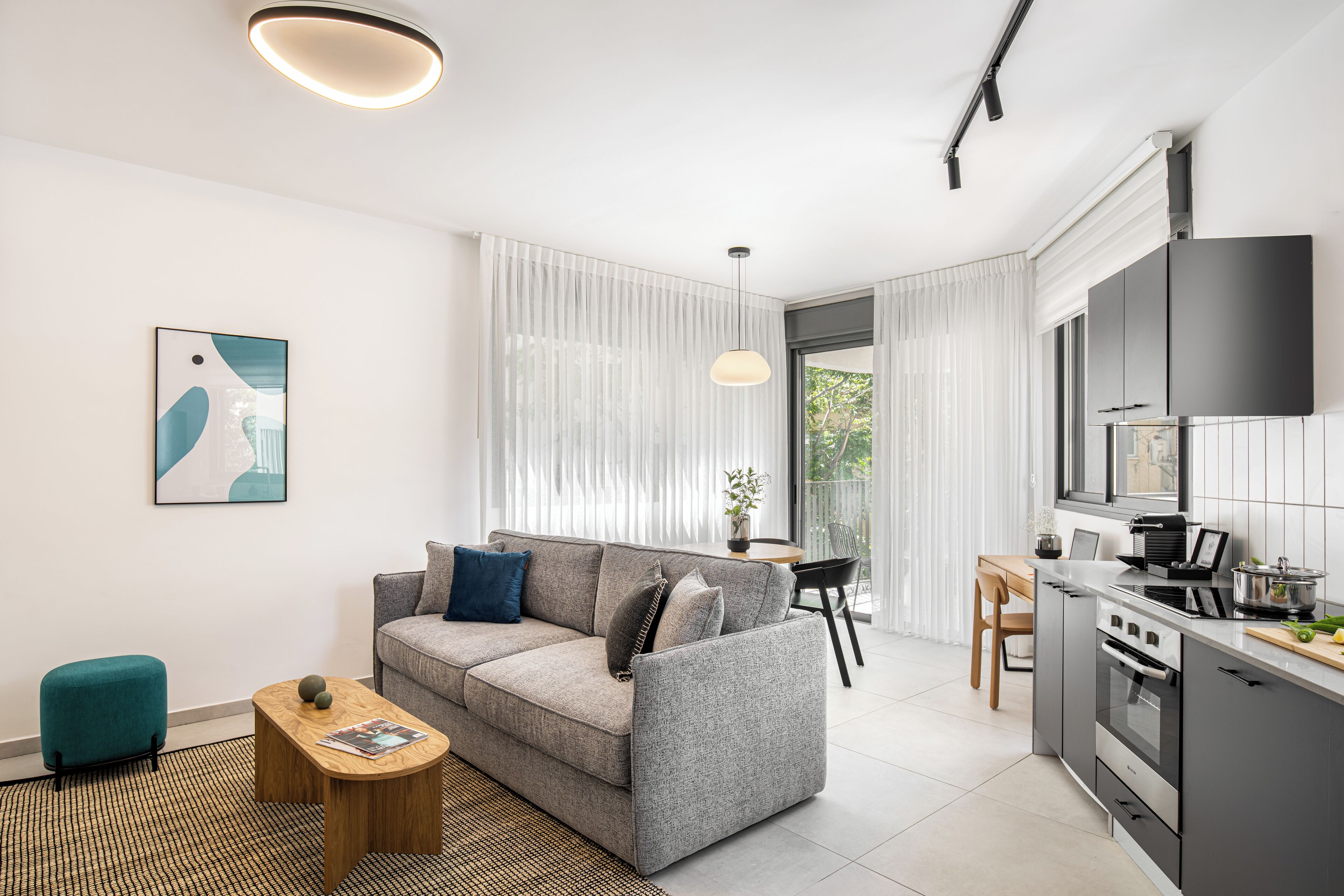A modern living room with a sofa, coffee table, and a dining area with a chair and table.