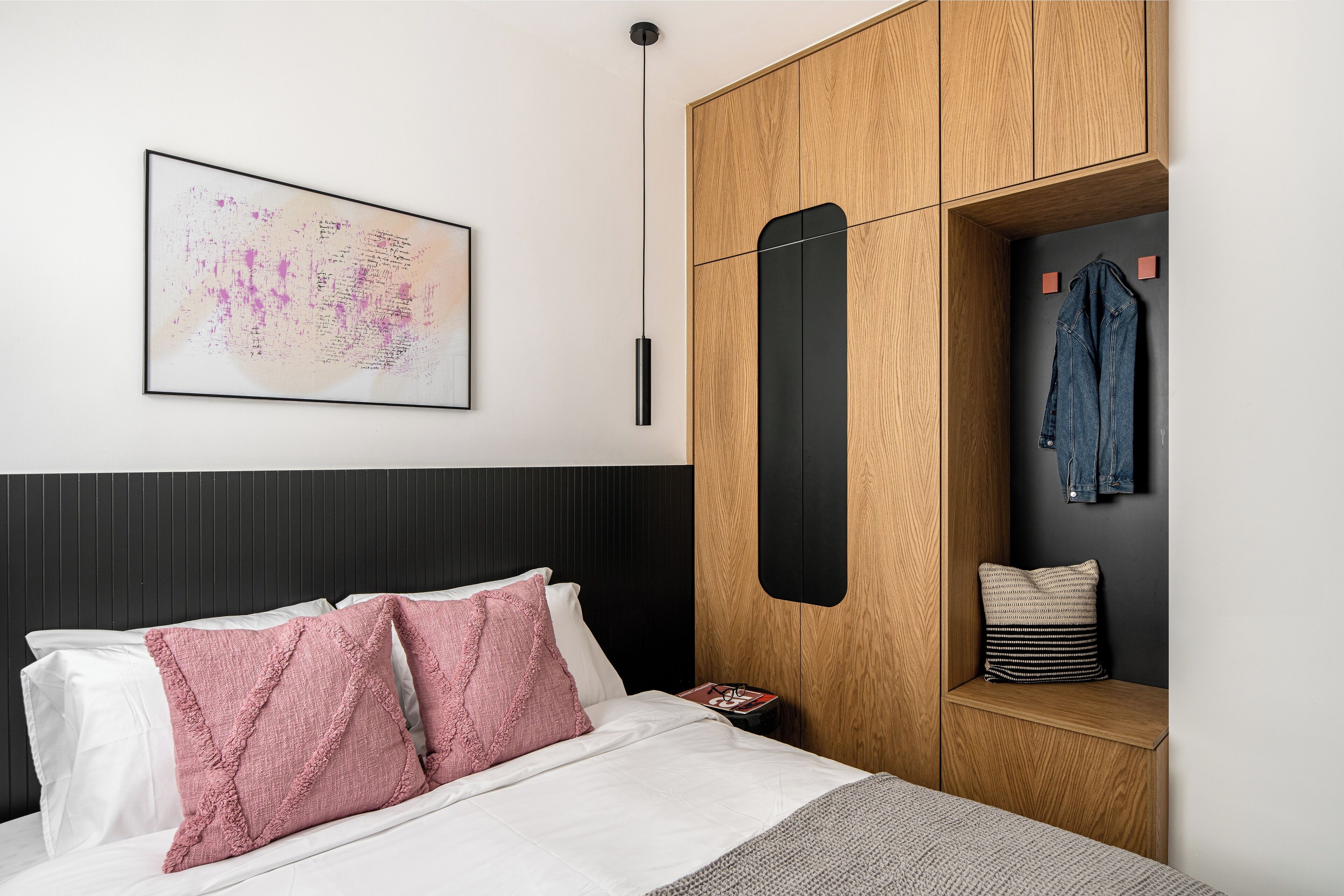 Een moderne slaapkamer met een bed, een houten garderobe en een kledingrek.
