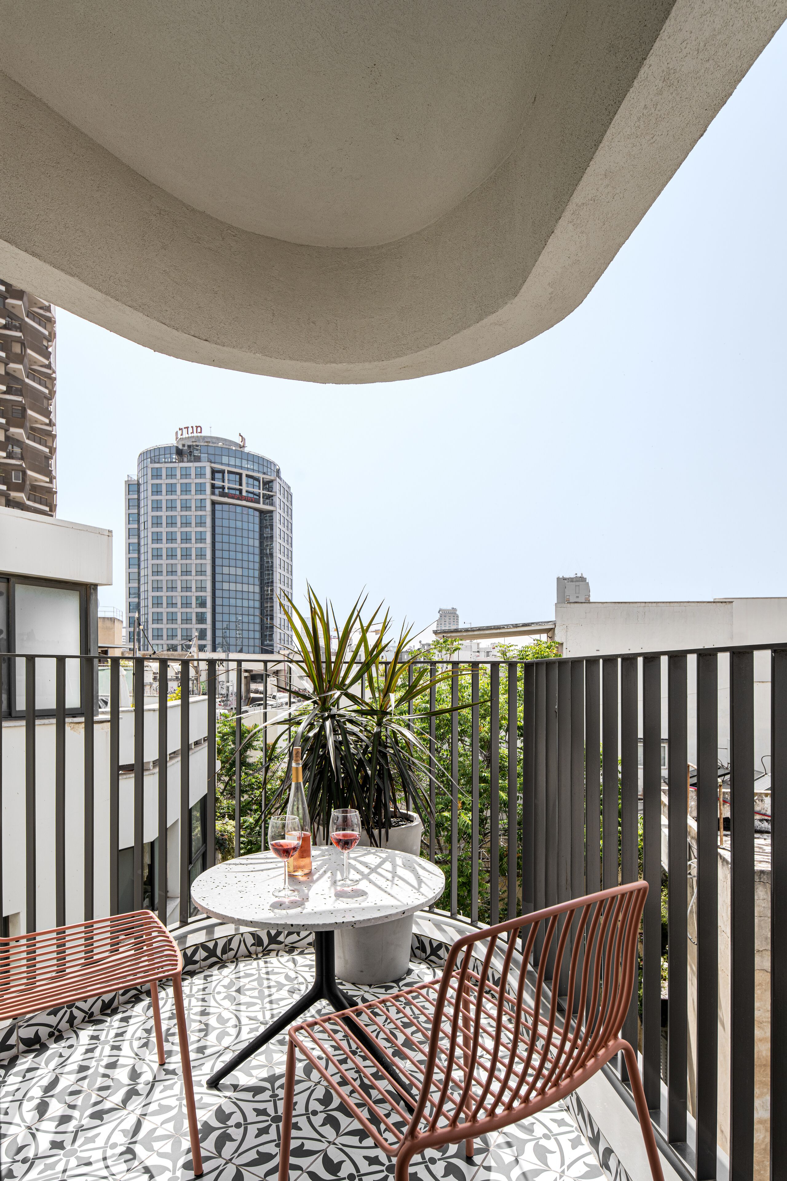 Une terrasse sur le toit avec une table ronde, deux chaises et un pot de fleurs.