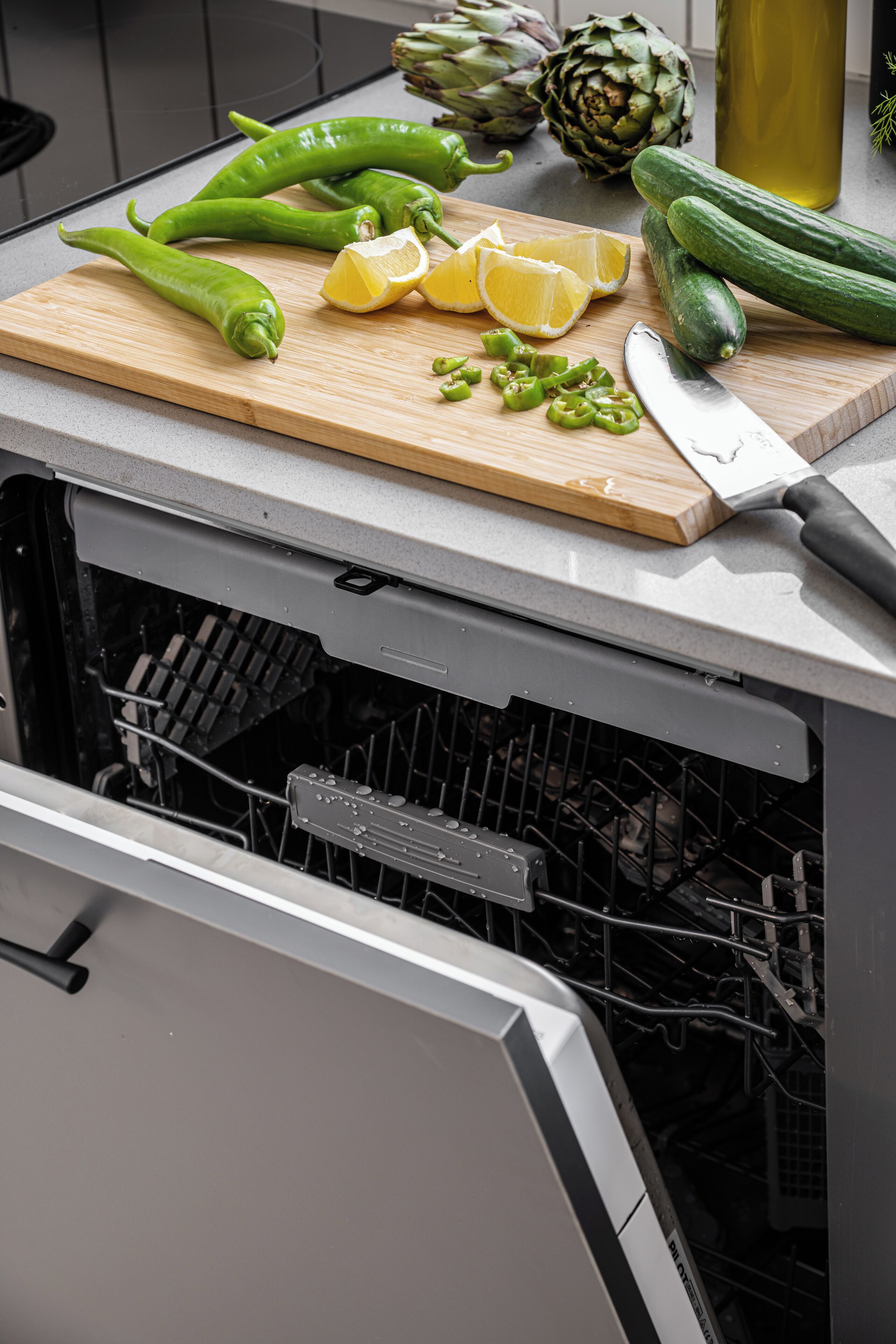 A kitchen counter with a cutting board, vegetables, and a knife.