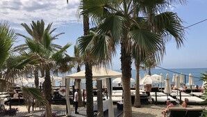 Ein Strandresort mit Liegestühlen, Palmen und Blick aufs Meer.