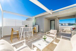 A modern outdoor living area with a dining set, seating, and a view of the cityscape.