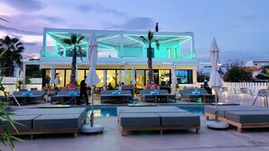 Ein modernes Hotel mit Poolbereich, Liegestühlen und Sonnenschirmen.