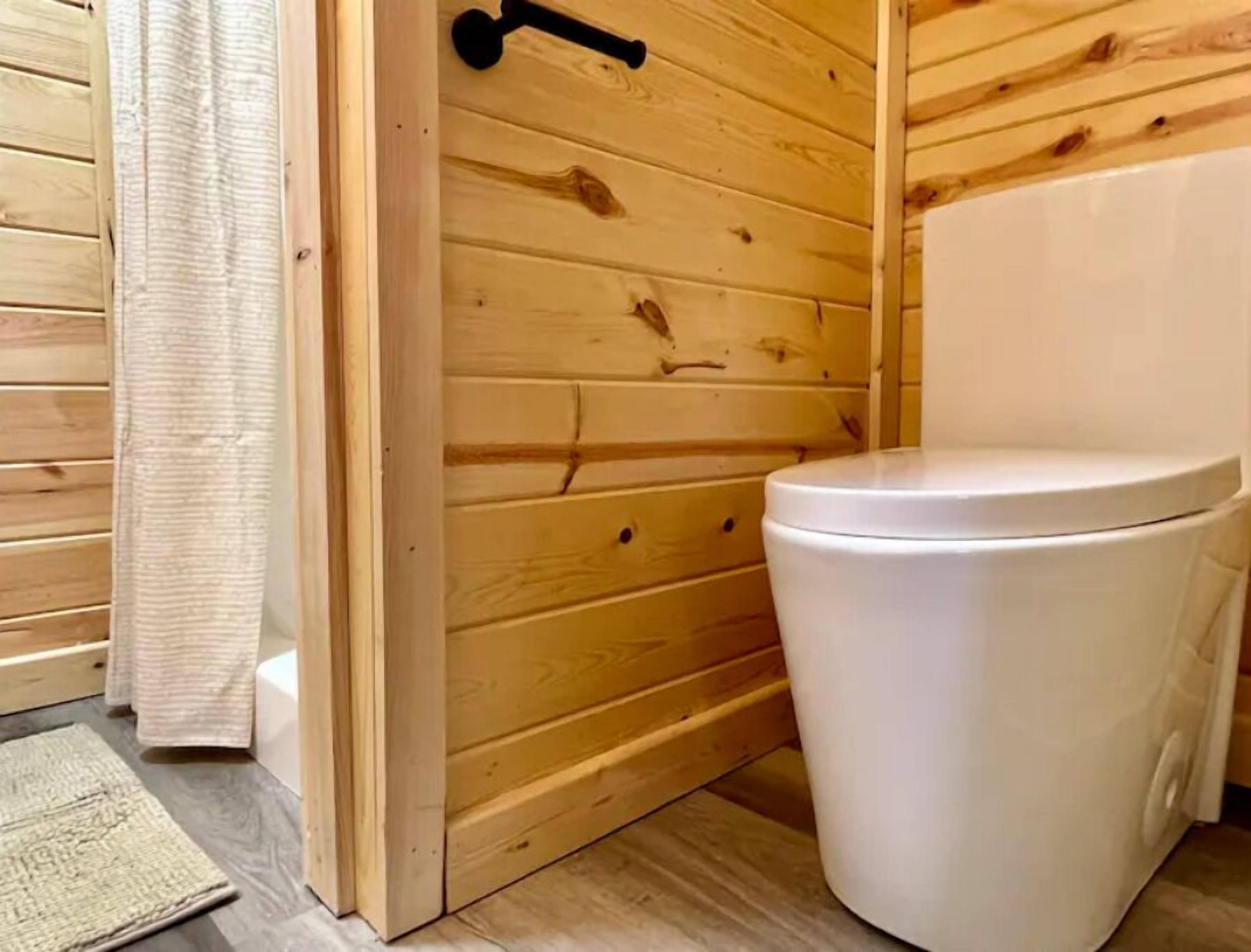 A wooden bathroom with a white toilet and a wooden door.