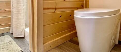 A wooden bathroom with a white toilet and a wooden door.