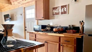 Een keuken met houten kastjes, een magnetron, een waterkoker en een koffiezetapparaat.