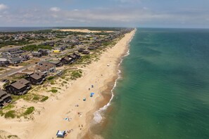 Vue aérienne d’une ville côtière avec des propriétés situées en bord de mer, une plage de sable et l’océan.