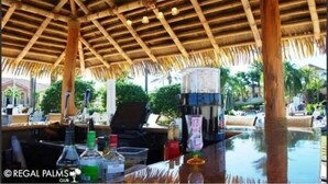 An outdoor bar area with a thatched roof, bar stools, and a pool. - Spacious & Modern 3BR Townhouse Near Disney w/ Pool & Lazy River! (Davenport)