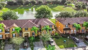 A residential area with houses, a green lawn, and a body of water. - Spacious & Modern 3BR Townhouse Near Disney w/ Pool & Lazy River! (Davenport)