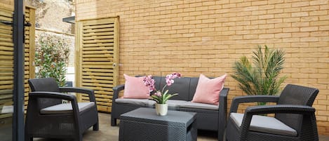 An outdoor seating area with wicker furniture and a potted plant.
