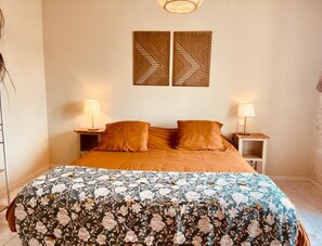 A bedroom with a large bed, two nightstands, two wall-mounted lamps, and two decorative wall panels.