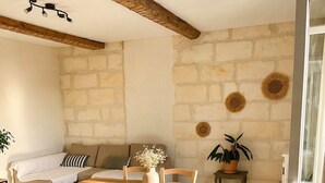 A dining area with a wooden table and chairs, a sofa, and a stone wall.