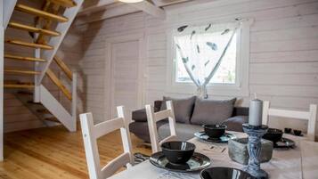 Ein Essbereich mit einer Holztreppe, weißen Wänden und einem Fenster mit Vorhang.