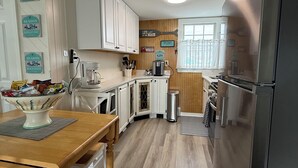 A compact kitchen with white cabinets, a wooden dining table, and a stainless steel refrigerator. - Beachside, convenient, Coastal Decor Surf City Apartment, family friendly!! (Surf City)
