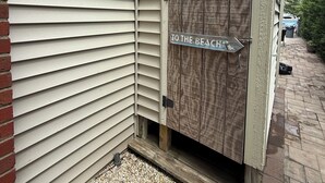 Casa con baño, un letrero indica ducha exterior y otro señala la playa.