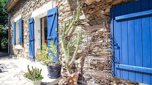 A stone building with blue shutters and potted plants. - Bastide nestled in the heart of nature (La Garde-Freinet)
