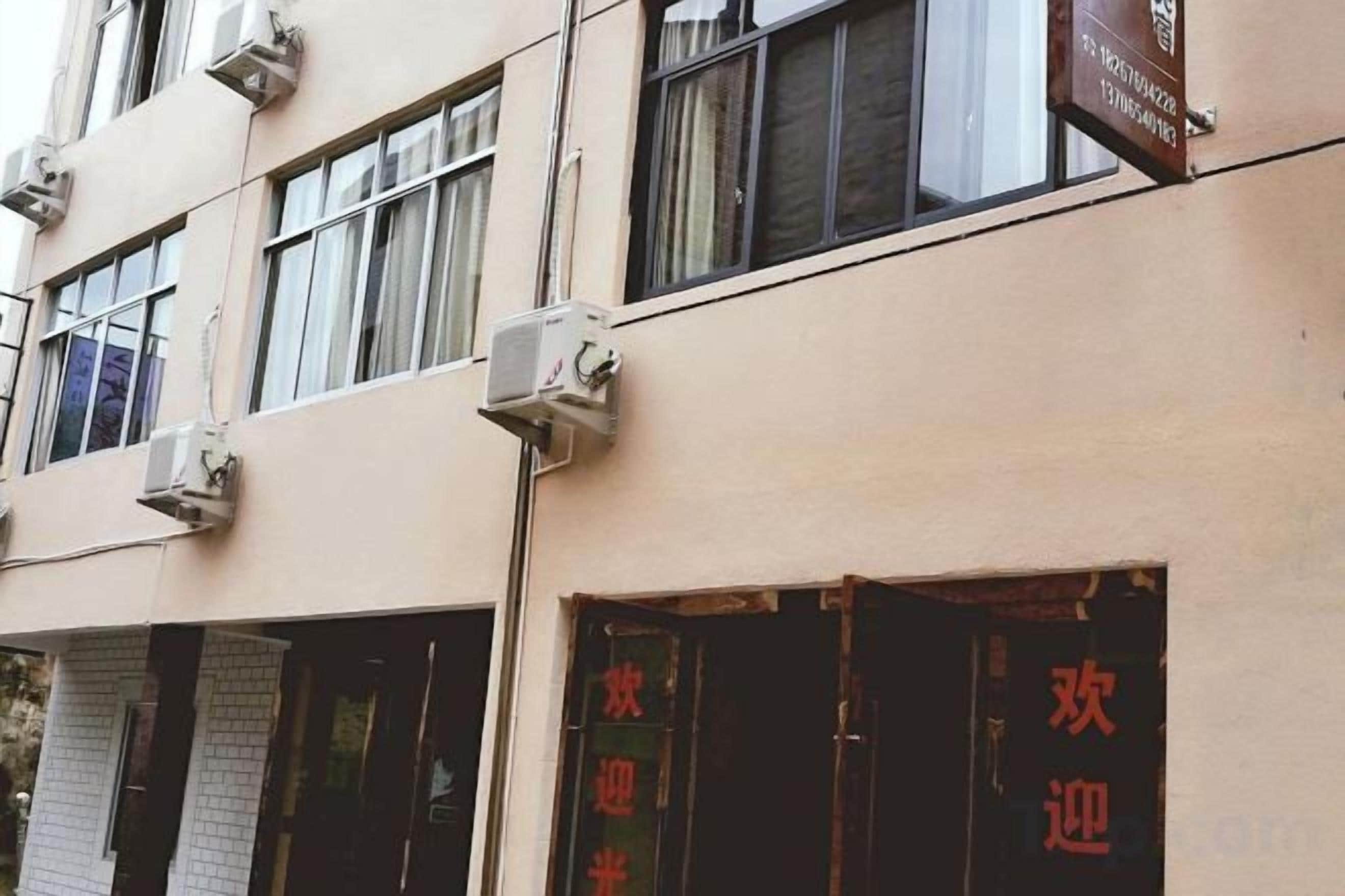 A building facade with multiple windows, some with air conditioning units, and a sign with Chinese characters.