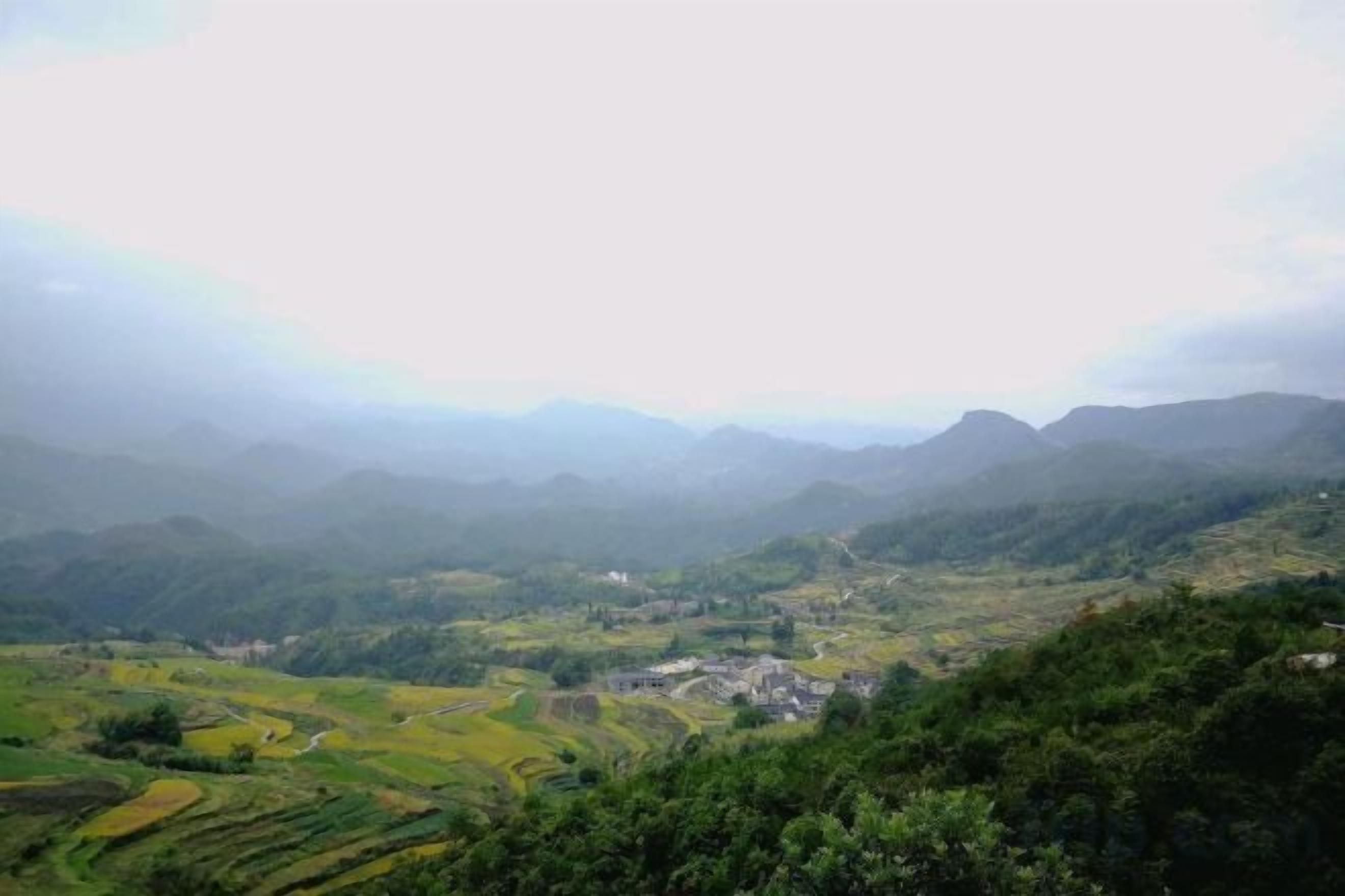 A mountainous landscape with terraced fields and a small settlement.