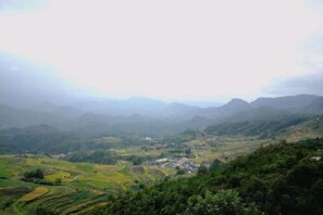 Un paysage montagneux avec des champs en terrasses et un petit village.