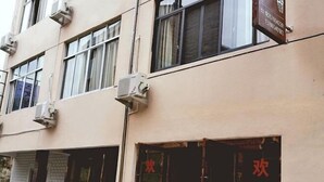 Une façade d’immeuble ornée de plusieurs unités de climatisation et d’une enseigne aux lettres rouges.