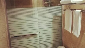 Une salle de bain avec une paroi en verre, des toilettes et un porte-serviettes avec des serviettes.
