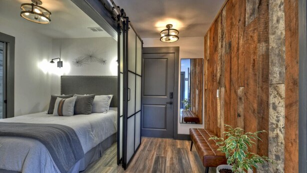 A modern bedroom with a bed, bedside tables, and a wooden wall panel. - Modern Rustic Loft Suite in Downtown Blue Ridge (Blue Ridge)