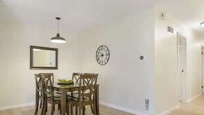 Un coin repas avec une table et des chaises, une horloge murale et un luminaire suspendu.