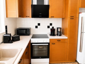 Eine moderne Küche mit Mikrowelle, Toaster, Kaffeemaschine, Backofen und Kühlschrank.