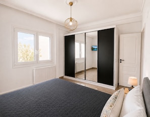 Ein Schlafzimmer mit einem Bett, einem Kleiderschrank, einem Fernseher und einem Fenster.