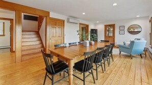 Un comedor amplio con una mesa y sillas de madera, una escalera y una silla azul a rayas.