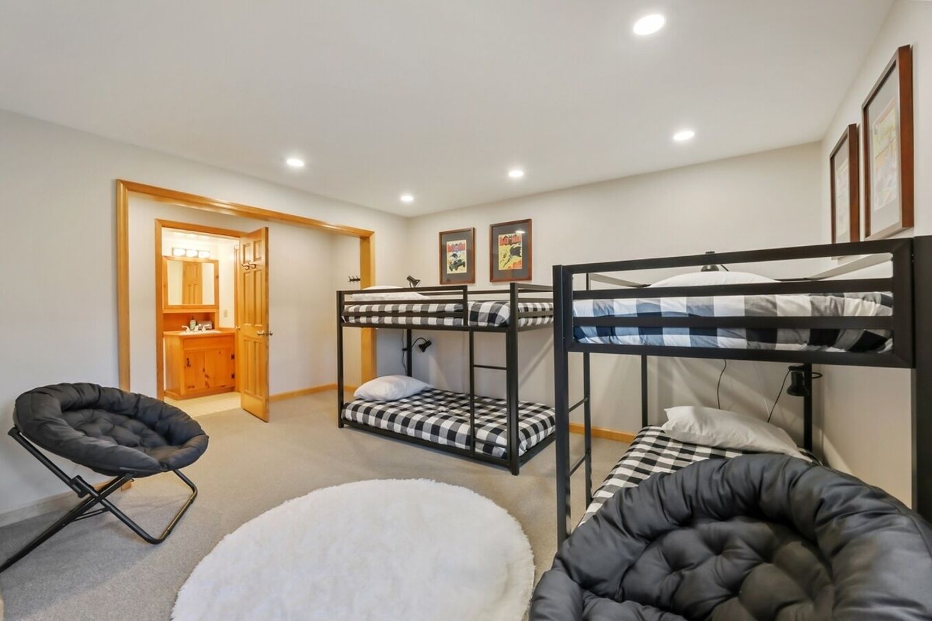 A room with bunk beds, a chair, and a small white round rug.