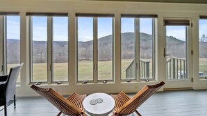 Una habitación con ventanas amplias, una mesa redonda y dos sillones.
