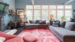 Una sala de estar acogedora con un sofá modular, un tapete rojo estampado y un ventanal de varios paneles.