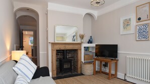 A living room with a fireplace, a sofa, a TV on a stand, and artwork on the wall. - 5 East Street  (Rye)