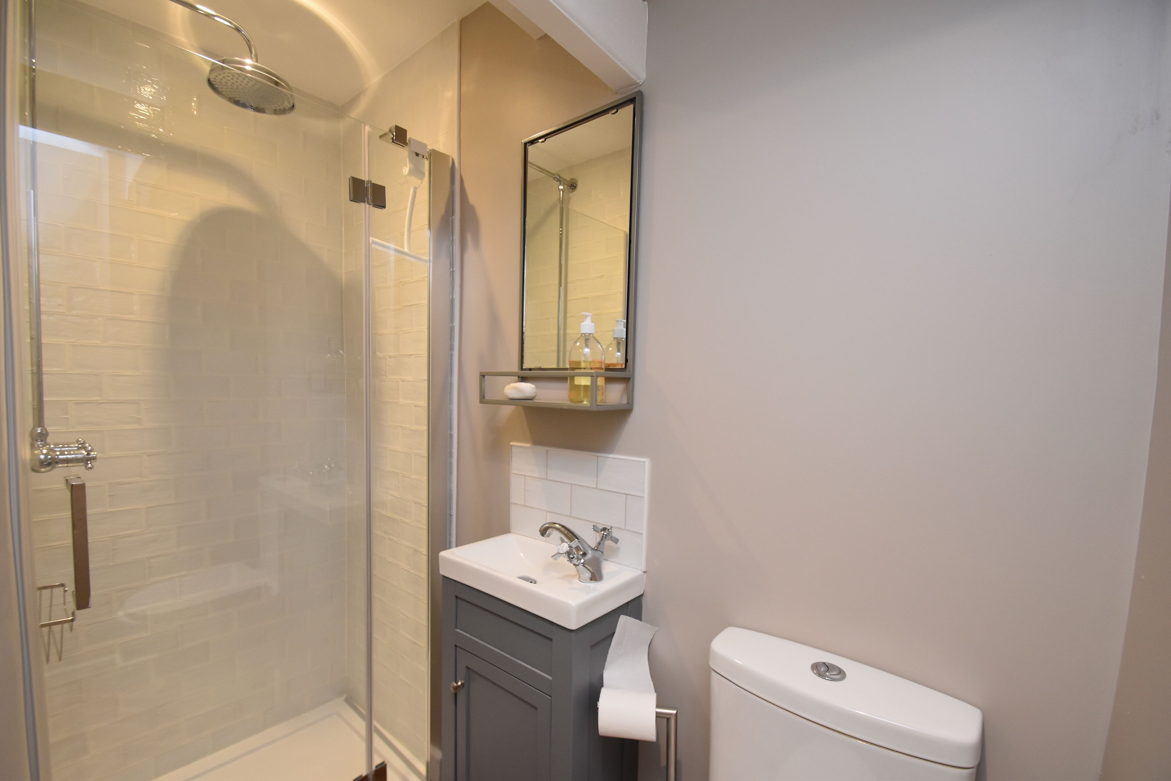 Une salle de bain avec une douche à parois de verre, un lavabo blanc, un miroir et des toilettes.