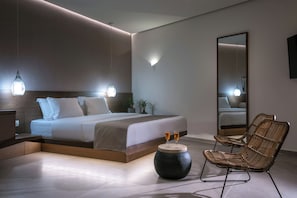 Ein modernes Schlafzimmer mit einem großen Bett, Nachttischlampen, einem runden Tisch mit zwei Gläsern und einem großen Spiegel.