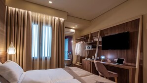 Une chambre d’hôtel avec deux lits, un bureau avec un ordinateur portable, une télévision et une armoire.
