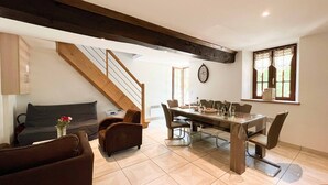 A dining area with a wooden table, chairs, and a clock on the wall. - Small village house in the heart of Normandy! (Ferrières-la-Verrerie)