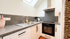 A modern kitchen with a built-in dishwasher, a coffee maker, and a stainless steel range hood. - Small village house in the heart of Normandy! (Ferrières-la-Verrerie)