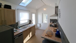Une cuisine moderne dotée d’une lucarne, de meubles en bois, d’un four encastré et d’une grande fenêtre.