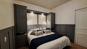 Une chambre à coucher avec un lit, une tête de lit intégrée et une porte.