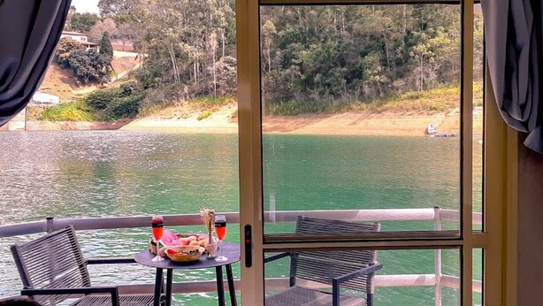 Un balcón con mesa y sillas que da a una masa de agua y una playa.