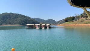Una hilera de casas flotantes sobre un lago tranquilo, con un promontorio boscoso al fondo.