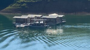Una casa flotante de varios niveles, conectada por pasarelas, ubicada en un lago tranquilo rodeado de vegetación.