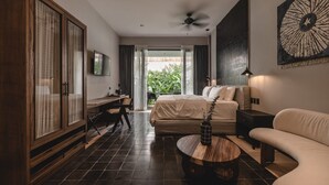 Et moderne hotelværelse med seng, skrivebord, sofa og et stort vindue med gardiner.