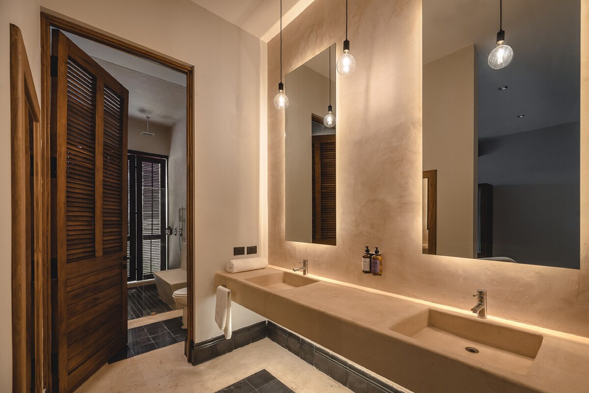 Une salle de bain moderne avec un double vasque, un grand miroir et des luminaires suspendus.