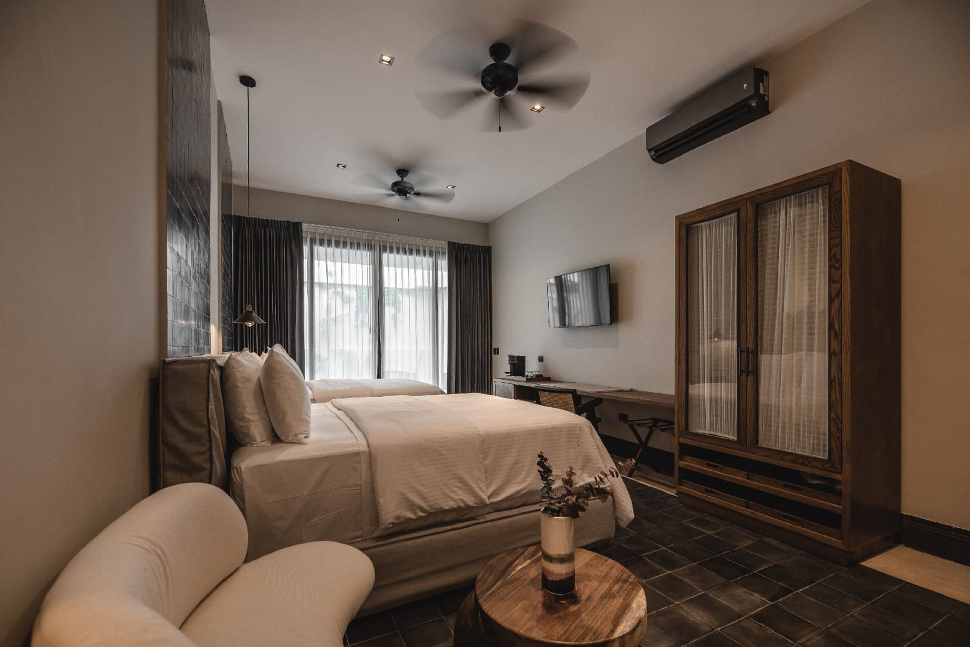 Una habitación de hotel moderna con una cama grande, un escritorio, un televisor y un armario.
