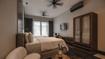 Una habitación de hotel moderna con una cama grande, un escritorio, un televisor y un armario.